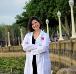 student in lab coat by a bridge