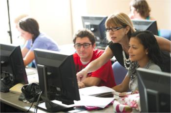 teacher aiding students in computer lab