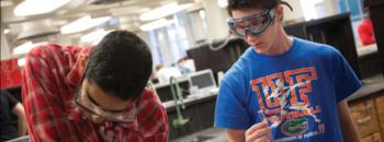 students in lab coats conducting an experiment at 'uf'