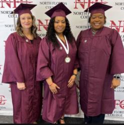 three graduates in front of 'north florida college' banner