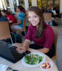 student with laptop and food at table