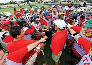 lacrosse team in a huddle with coach