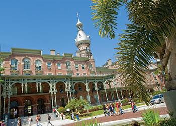 historic building surrounded by students and palm trees