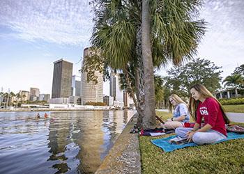 students studying by a river with city view