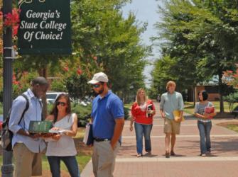 students walking on campus with sign 'georgia's state college of choice!'