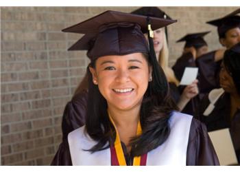 smiling graduate in cap and gown with others