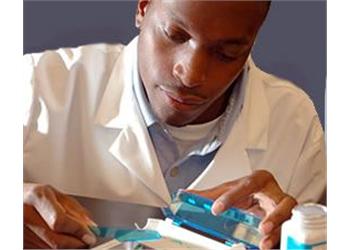 focused man in lab coat using a pipette