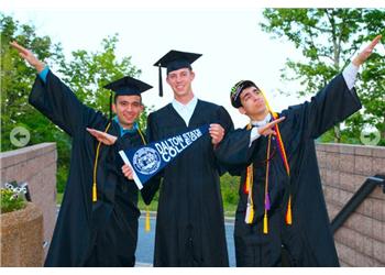 three graduates in caps and gowns celebrating