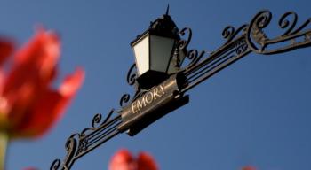 lamppost with 'emory' sign and red tulips against blue sky