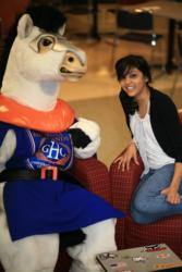 student posing with a mascot holding a GHC laptop