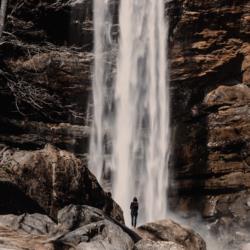 person standing before a natural waterfall