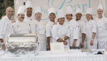 group of chefs with 'pearl' sign posing behind banquet table