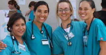 four smiling female healthcare workers in scrubs