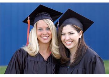 two graduates smiling, wearing caps and gowns