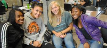 four students smiling at a table