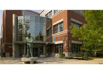 statue in front of modern building with blue signs