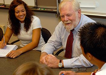 professor shaking hands with a student in a classroom