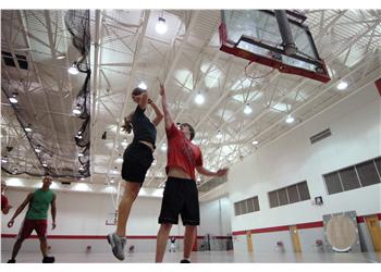 students playing basketball in gymnasium