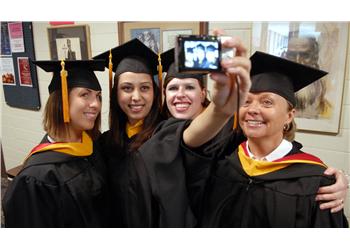 graduates taking a selfie in caps and gowns