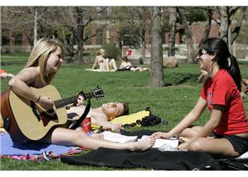 students with guitar on campus lawn