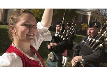 woman in traditional dress near bagpipe players