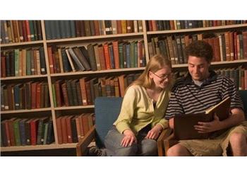 two students reading a book in the library