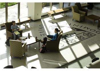 students in a lounge with sunlight casting university logo shadows