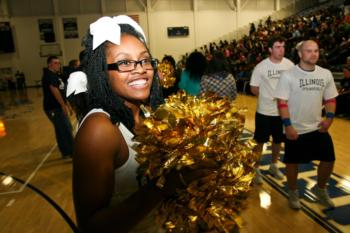 cheerleader smiling with pompoms at a sports event