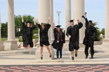 graduates jumping joyfully near a colonnade