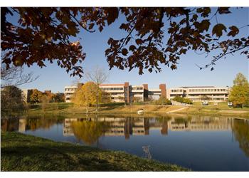 campus buildings across a lake with autumn foliage