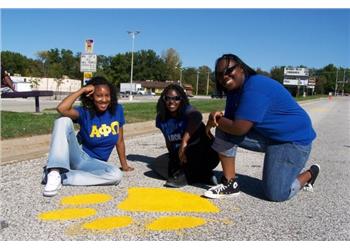 three individuals crouching by road painting