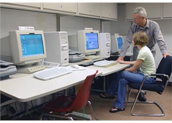 two people using vintage computers in a classroom