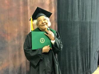 elderly graduate smiling in cap and gown, holding diploma