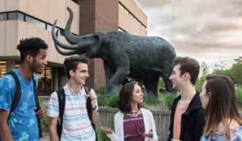 students standing by a statue of a bison