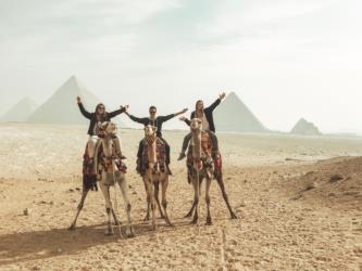 people on camels in front of pyramids