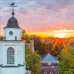 sunset behind college buildings with a clock tower