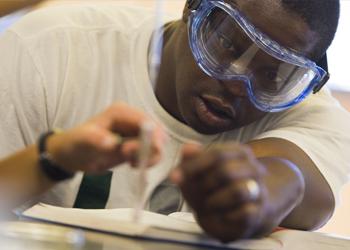 student in safety goggles conducting an experiment