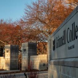 entrance sign to 'Grinnell College' with trees in the background