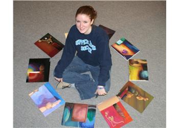 student sitting on floor with art projects