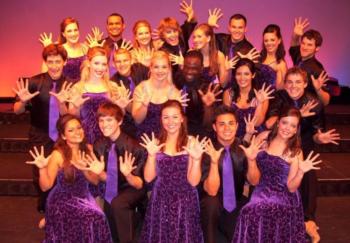 group of people in formal attire smiling with hands up