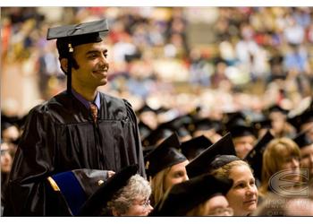 graduate smiling in commencement gown among peers