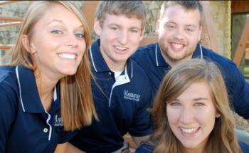 four people in blue shirts smiling outdoors