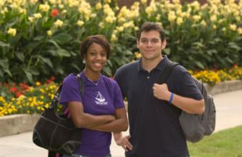 two students smiling with a background of flowers and greenery