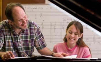 man teaching young woman at a piano