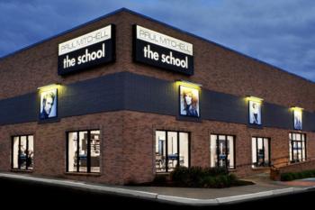 exterior of a building at dusk with lit signage 'paul mitchell the school'