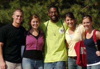 five smiling students posing outdoors