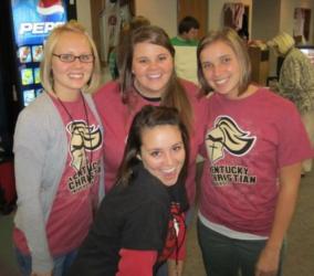 four smiling people wearing 'kentucky christian' t-shirts