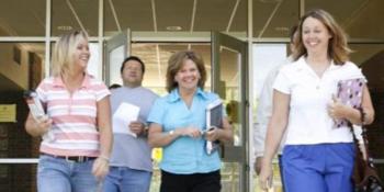 four adults smiling while walking out of a building