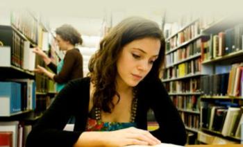 student studying in a library with others in background