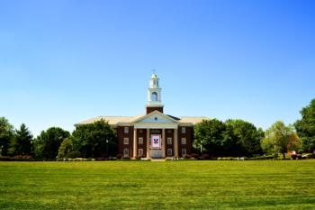 brick building with a central clock tower on a sunny day